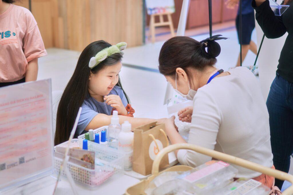 A woman getting her hand painted to a girl